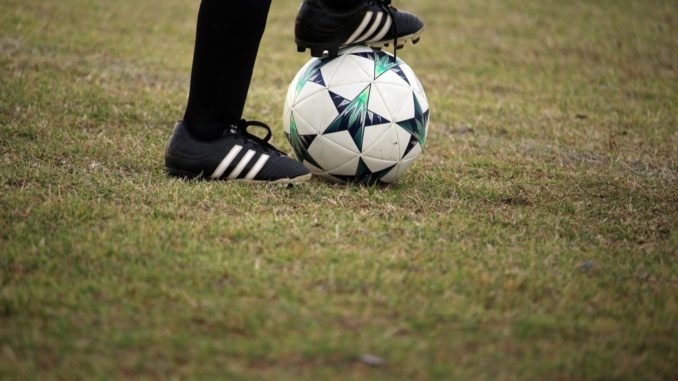 Une joueuse de football avec le pied posé sur le ballon.